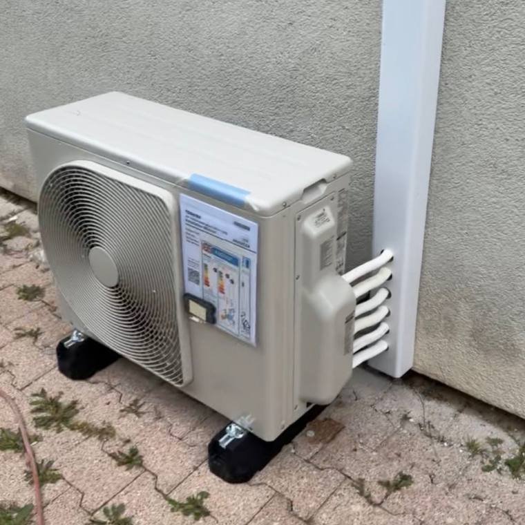 Groupe extérieur de climatisation installé sur plots contre une façade