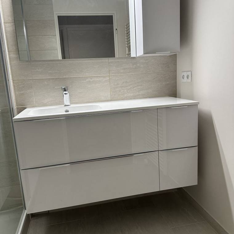 Meuble vasque et miroir lumineux installés dans une salle de bain rénovée